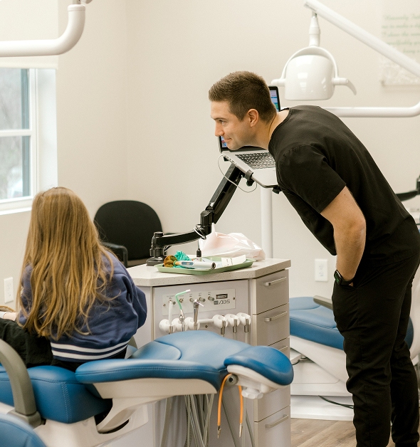 Orthodontist reviewing a young patient's records on a chairside monitor
